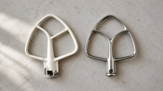 Worn coated KitchenAid flat beater next to a new stainless steel replacement paddle